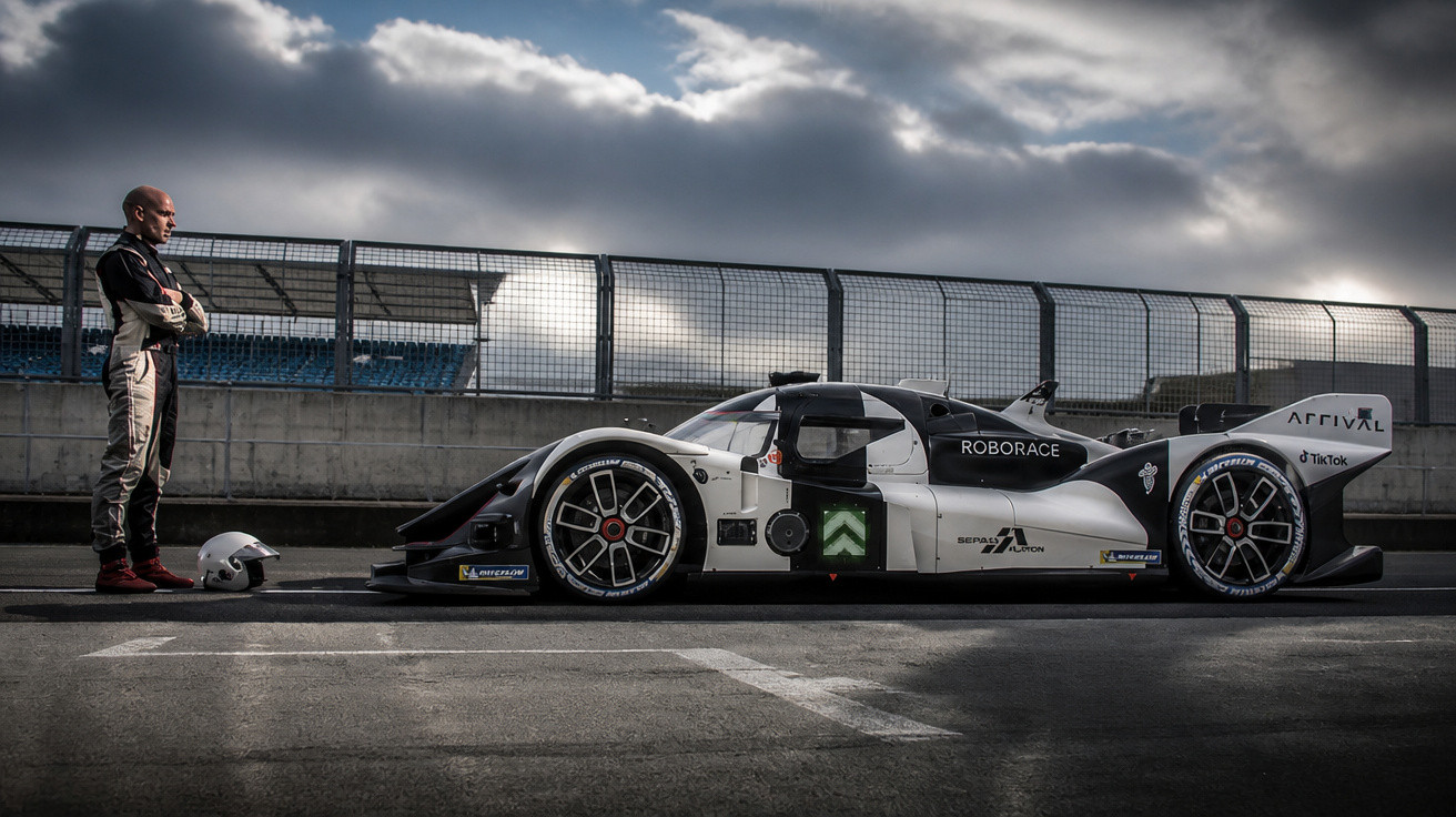Voiture de course autonome Roborace noire et blanche, pilote debout avec casque sur piste sous ciel nuageux.