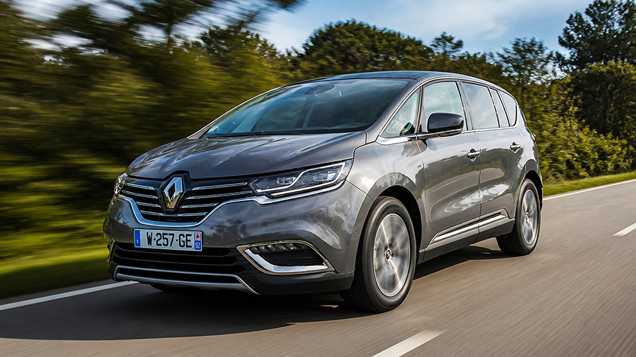 Voiture familiale Renault grise roulant sur une route en campagne sous ciel partiellement nuageux.